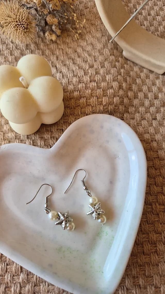 Delicate pearl earrings on a heart-shaped dish